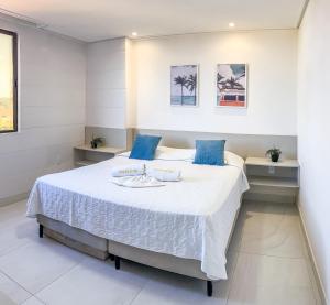 雅克南FLATS ENSEADA Do SOL的卧室配有带蓝色枕头的大型白色床