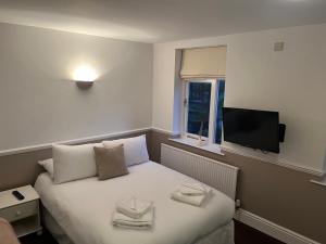 尼德姆马基特Limes hotel的酒店客房设有一张床铺,墙上配有电视。