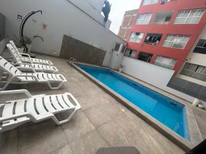利马Acogedor apartamento centrico, tranquilo con piscina的一座酒店,毗邻一座建筑,设有游泳池和躺椅