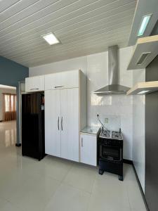 马卡帕Casa completa, suíte master com closet的厨房配有白色橱柜和黑炉。
