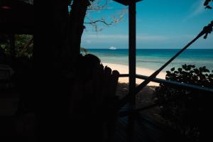 刁曼岛Swiss Cottage Tioman的坐在门廊上,望向海滩的人