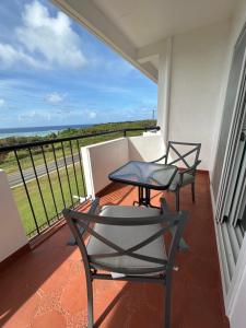 San RoqueMariana Suites的阳台上配有两把椅子和一张桌子,享有海景