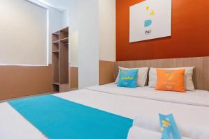 KrembanganSans Hotel Rajawali Surabaya by RedDoorz的一间卧室配有带橙色和蓝色枕头的床