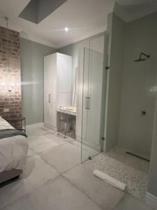 开普敦Two on Milner - ARUM COTTAGE - Stylish open-plan Guesthouse in Rondebosch的一间带玻璃淋浴间和一张床的卧室