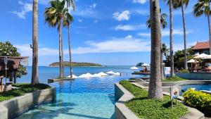 查汶Nora Buri Resort & Spa - SHA Extra Plus的一座棕榈树和海洋游泳池