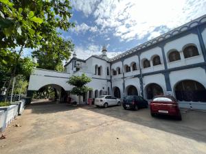 坦贾武尔Hotel TamilNadu - Thanjavur的白色的建筑,有汽车停在停车场