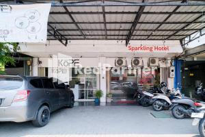 泗水RedDoorz at Sparkling Hotel Surabaya的停车场,停放汽车和摩托车,停在大楼前