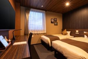御殿场市The Celecton Gotemba Interchange的酒店客房设有两张床、一张桌子和一台电视。