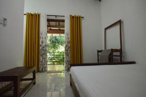 波隆纳鲁沃碧纳兰民宿的一间卧室配有床、镜子和黄色窗帘