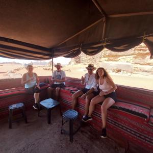 瓦迪拉姆Enad desert camp的一群坐在沙漠里公共汽车上的人