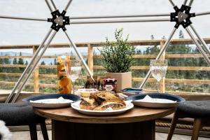 Sør-FronArctic Dome Gudbrandsdalen的一张桌子,上面有面包和酒杯,还有两台望远镜