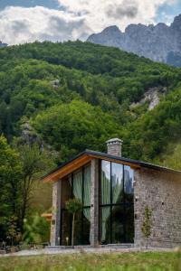 泰斯Villa Ujëvara e vogël的山前带大窗户的石头房子