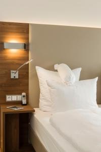 莱茵河畔路德维希港Living Apartments Ludwigshafen的一张带白色枕头的床和一张带台灯的桌子
