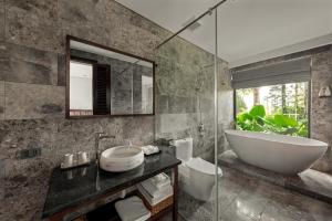 宁平Coco Island Villa & Hotel Ninh Bình的带浴缸、水槽和镜子的浴室