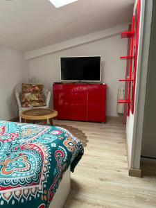 库列雷多Casa Vacacional La Coruña的一间卧室配有一张床,红色橱柜上配有电视