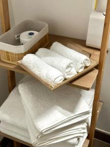 勒布朗-梅尼尔Perle rare « Le Cosy de CDG »的浴室架子上的一大堆毛巾