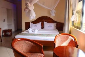 VoiTwo Oceans Hotel Voi的一间卧室配有一张带两把椅子和一张桌子的床。
