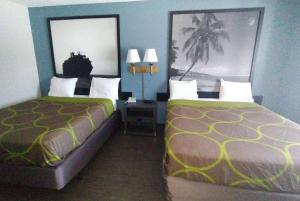达尼亚滩Super 8 Motel by Wyndham near Fort Lauderdale Arpt的酒店客房设有两张床和两盏灯。