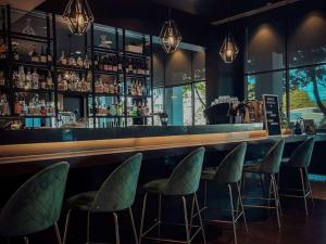 格伦韦弗利墨尔本诺富特格林威福利酒店的一间酒吧,配有绿色椅子和吧台