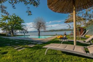 马焦内La Folaga del Trasimeno的一个带游泳池、长凳和遮阳伞的度假胜地