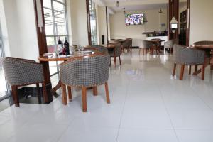 WoteParaiso Gardens Hotel的一间铺有白色瓷砖地板并配有桌椅的用餐室