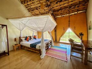 Murchison Falls National ParkMurchison Falls Bamboo Village的一间卧室配有一张带天蓬的床
