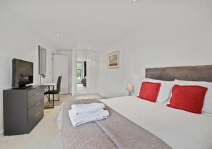 伦敦Cubo Farringdon的一间卧室配有一张带红色枕头的大床和电视。