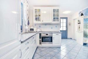格洛韦Ferienhaus-Seehund的白色的厨房配有白色橱柜和电器