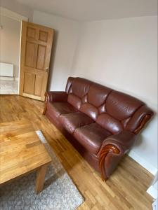 戈尔韦Cosy 4 Bedroom Galway House with Rear Garden Patio的客厅里一张棕色的皮沙发,配有桌子