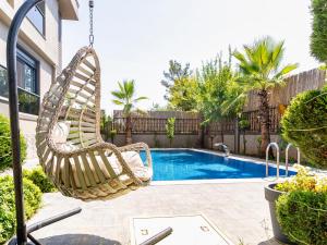 安塔利亚Lux Villa w Balcony Pool Sauna Garden in Antalya的游泳池旁的摇摆椅