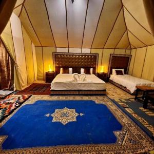 梅尔祖卡Luxury Desert Camp Merzouga的一间卧室配有一张床,帐篷内铺有蓝色地毯