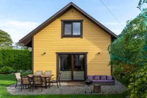 库雷萨雷Cosy Family Guesthouse with Sauna and Garden的黄色的房子,配有桌子和椅子