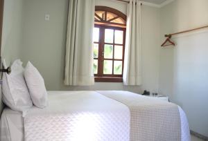 迪亚曼蒂纳POUSADA CAPIM LIMÃO的卧室配有白色的床和窗户。