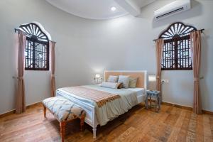 果阿旧城SaffronStays Amarah Pet-friendly Luxury Villa-Assagao, North Goa的一间卧室设有一张大床和两个窗户。