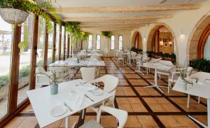 德尼亚Hotel Los Ángeles Denia的一间设有白色桌子和白色椅子的餐厅