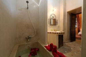 马拉喀什Riad en Exlusivité à 5min de la place jamaa el fna的浴室配有带红色鲜花的浴缸。