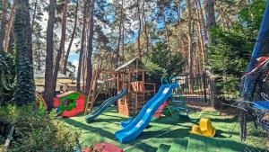 MoineştiComplex Parc Pini Moinesti的一个带滑梯的游乐场,位于一个树木繁茂的庭院内