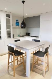墨尔本Modern Spacious 2BD2Bath - Stunning City Views!的白色的厨房配有白色的桌子和椅子