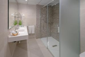 萨洛奥林巴斯宫酒店的一间带玻璃淋浴和水槽的浴室