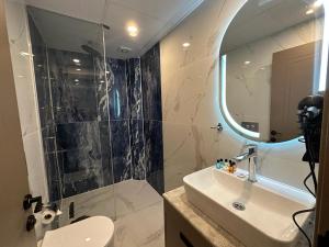 伊斯坦布尔Istanblu Hotel Ataşehir的浴室配有盥洗盆和带镜子的淋浴
