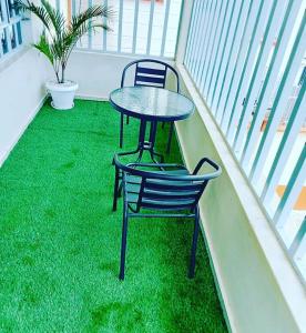 基苏木Sofitel 4 bedrooms maisonette Milimani的绿草阳台的桌子和椅子