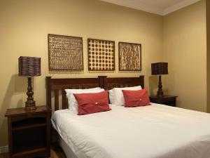 KirkwoodUpper Room Guesthouse的一间卧室配有一张带红色枕头的床和两盏灯。