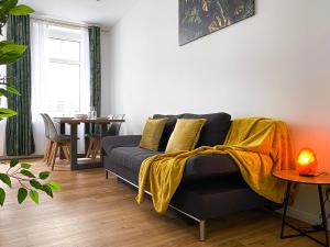 莱比锡Freundliche Ferienwohnung mit Regendusche, Küche, Waschmaschine&Trockner, TV, WLAN的客厅配有沙发和黄色毯子