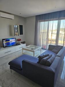 圣保罗湾城Double bedroom in shared Penthouse Apartment - Seabreeze Terraces的客厅配有蓝色的沙发和电视