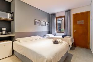 圣保罗Studio 2 Pinheiros by Oba的酒店客房设有两张床和窗户。