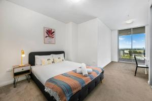 悉尼Spacious 2 beds Apt near Airport的一间卧室配有一张床、一张书桌和一个窗户。