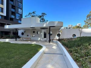 悉尼Adorable 2B Apt near Macquarie Uni的现代化的白色房屋设有庭院和草地。