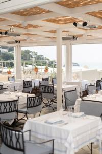 卡普里卡纳斯塔酒店的餐厅设有白色的桌椅和窗户。