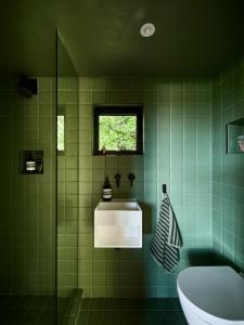巴斯Bay House Studio的绿色瓷砖浴室设有浴缸和水槽