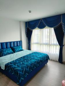 Ban Khlong SamrongSupalai City Resort的一间卧室配有蓝色的床、蓝色床单和窗户